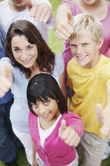 Young friends giving thumbs up. Photographe : momentimages