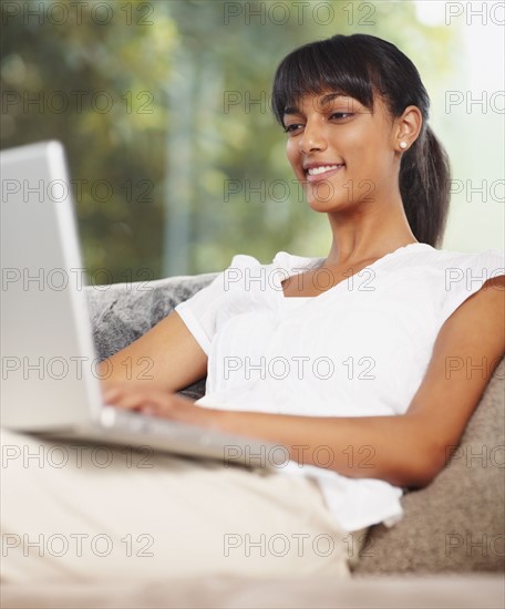 Young woman working on laptop. Photographe : momentimages