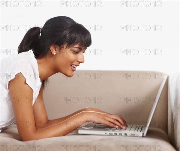 Young woman typing on laptop. Photographe : momentimages