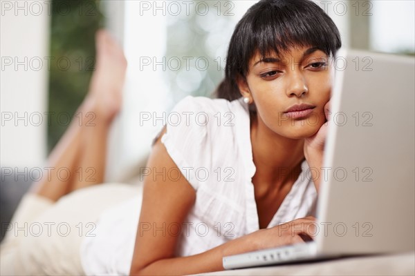 Young woman typing on laptop. Photographe : momentimages