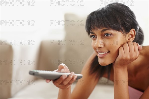 Young woman holding remote control. Photographe : momentimages