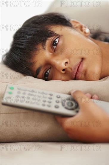 Young woman holding remote control. Photographe : momentimages