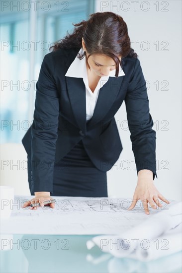 Businesswoman looking at blueprints. Photographe : momentimages