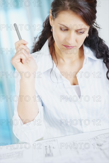 Woman looking at blueprints. Photographe : momentimages