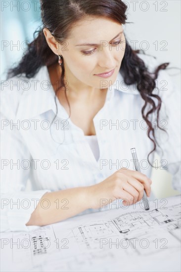 Woman looking at blueprints. Photographe : momentimages