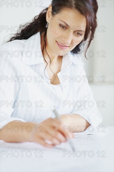 Woman looking at blueprints. Photographe : momentimages