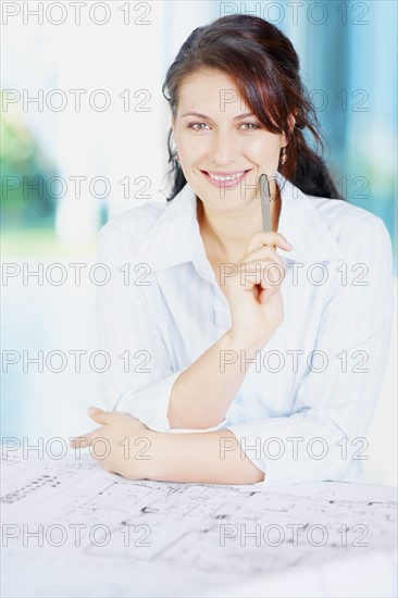 Woman looking at blueprints. Photographe : momentimages