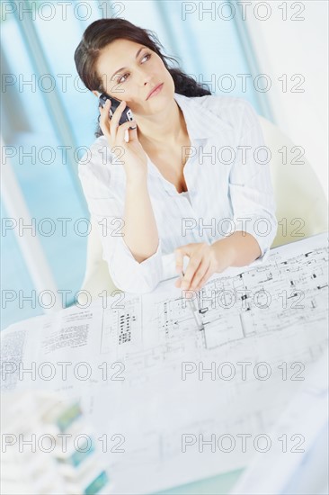 Woman looking at blueprints. Photographe : momentimages