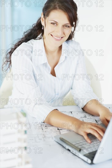 Woman typing on laptop. Photographe : momentimages