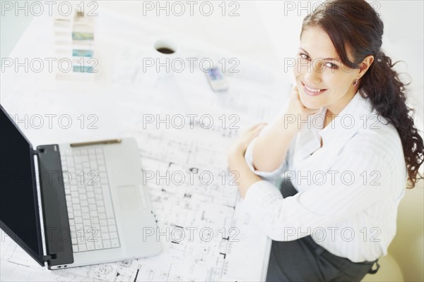 Woman sitting at desk. Photographe : momentimages