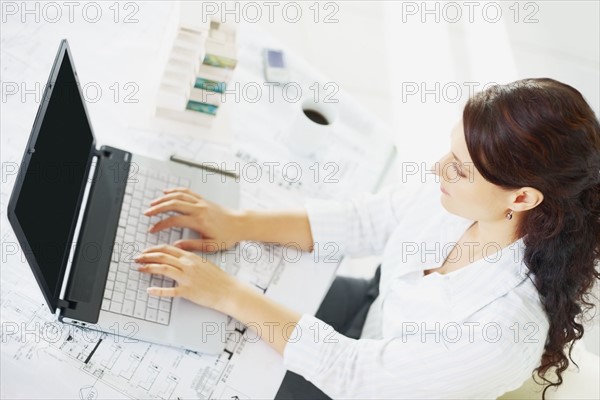 Woman typing on laptop. Photographe : momentimages