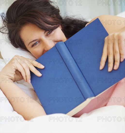 Woman reading in bed. Photographe : momentimages