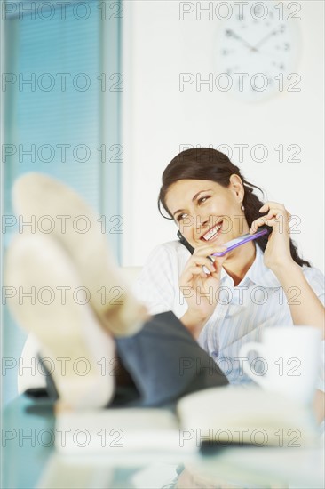 Relaxed woman sitting at desk. Photographe : momentimages