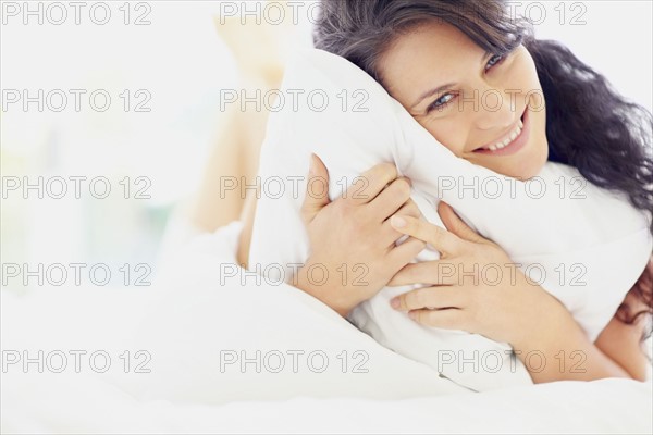 Woman holding pillow. Photographe : momentimages