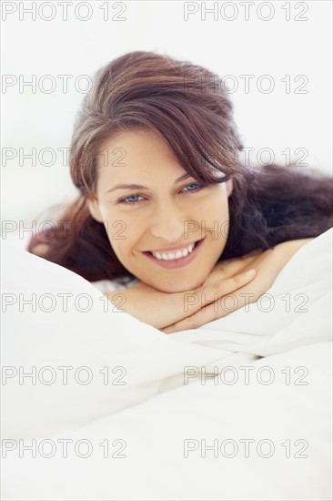 Woman relaxing on bed. Photographe : momentimages