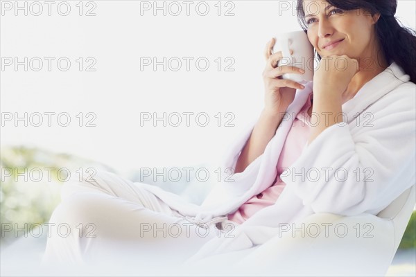 Woman in bathrobe drinking coffee. Photographe : momentimages