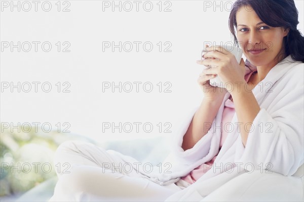 Woman in bathrobe drinking coffee. Photographe : momentimages