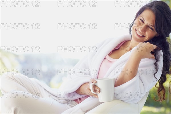 Woman in bathrobe drinking coffee. Photographe : momentimages