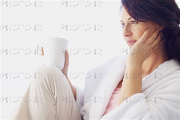 Woman in bathrobe drinking coffee. Photographe : momentimages