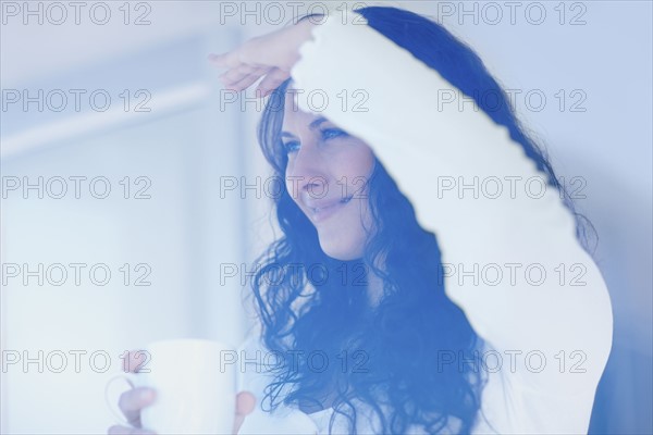 Woman looking out window. Photographe : momentimages