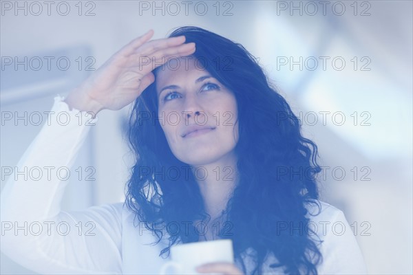 Woman looking out window. Photographe : momentimages