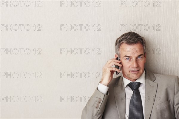 Businessman talking on cellular phone. Photographe : momentimages