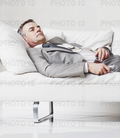 Businessman resting on couch. Photographe : momentimages