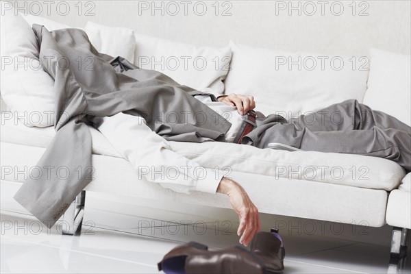 Businessman napping on couch. Photographe : momentimages