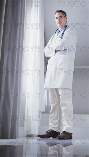 Doctor standing in front of window. Photographe : momentimages