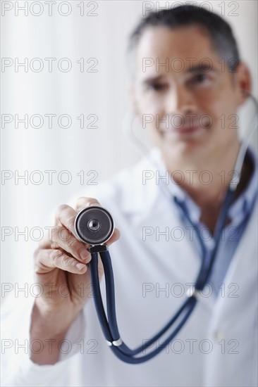 Doctor holding stethoscope. Photographe : momentimages