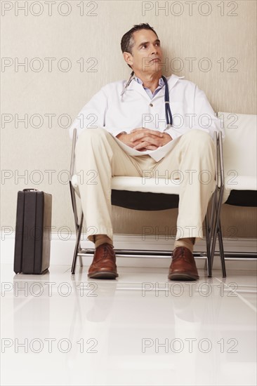 Doctor sitting in waiting room. Photographe : momentimages