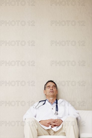 Doctor sitting in waiting room. Photographe : momentimages