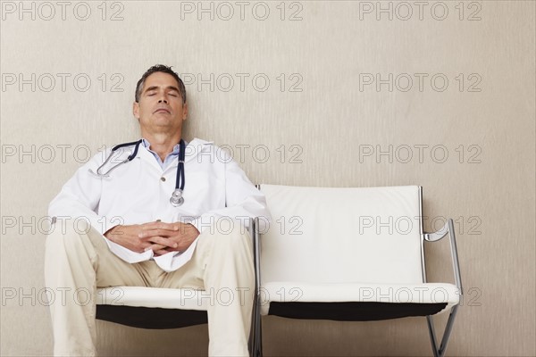 Doctor sitting in waiting room. Photographe : momentimages