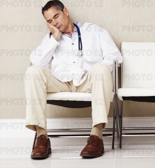 Doctor sitting in waiting room. Photographe : momentimages