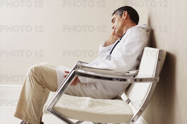 Doctor sitting in waiting room. Photographe : momentimages