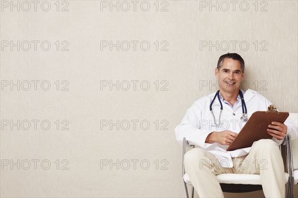 Doctor sitting in waiting room. Photographe : momentimages