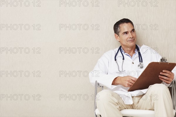 Doctor sitting in waiting room. Photographe : momentimages