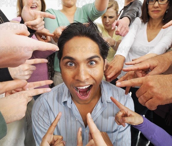 Group of people pointing at one person. Photographe : momentimages