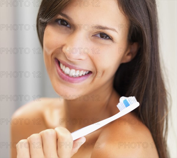 Woman holding a toothbrush. Photographe : momentimages