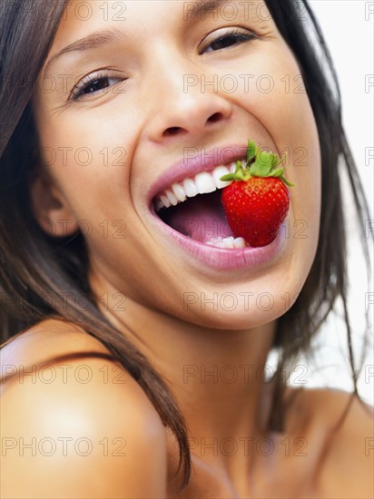 Woman eating strawberry. Photographe : momentimages