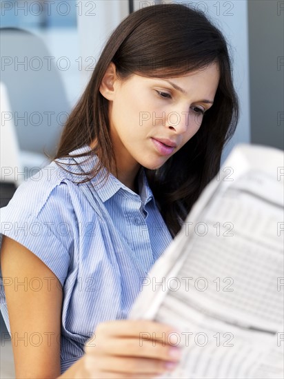 Woman reading newspaper. Photographe : momentimages