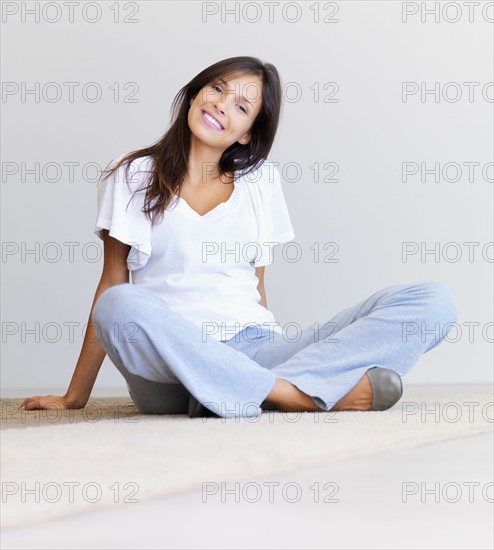 Woman sitting cross legged on floor. Photographe : momentimages