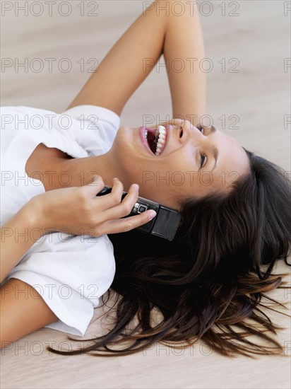 Woman laughing while talking on cellular phone. Photographe : momentimages