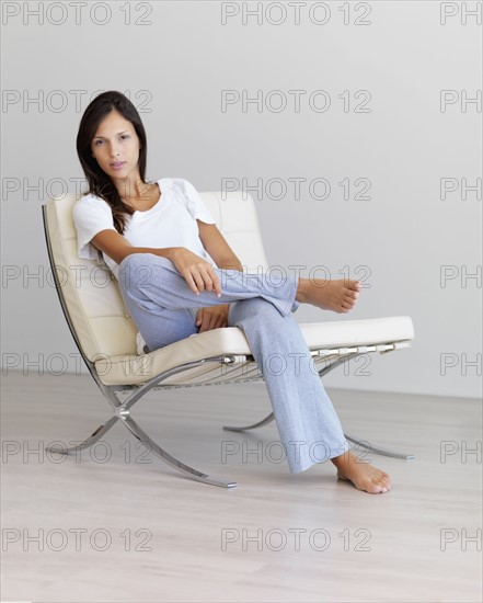 Relaxed woman sitting on modern chair. Photographe : momentimages