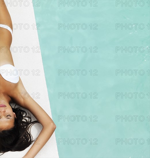 Woman sunbathing beside pool. Photographe : momentimages