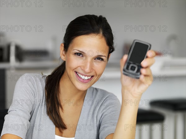 Woman holding cellular phone. Photographe : momentimages