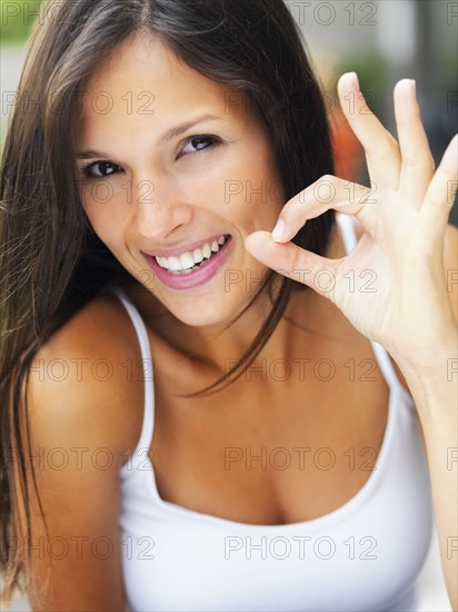 Woman giving okay sign. Photographe : momentimages