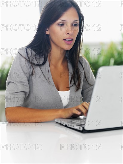 Woman typing on laptop. Photographe : momentimages