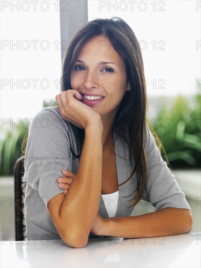Beautiful woman sitting at patio table. Photographe : momentimages
