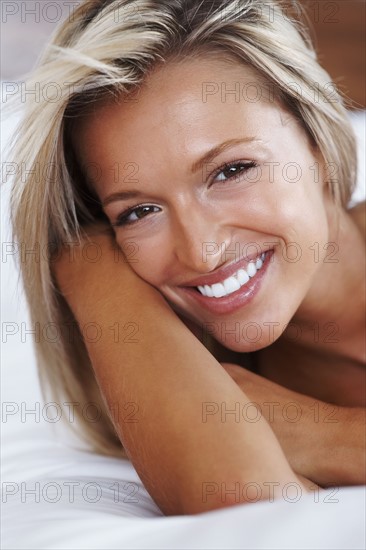 Blonde woman lying on bed. Photographe : momentimages